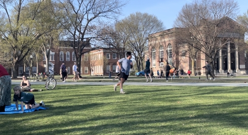 Students running around and playing games on the green.