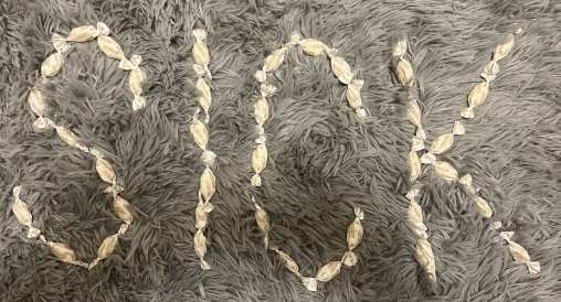 A photo of cough drops spelling out "SICK" on the ground.