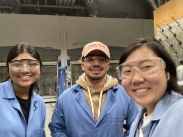 students smiling in lab coats and goggles 