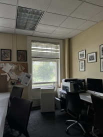 A photo of The Dartmouth's office. There are several office chairs, a bulletin board full of papers, and computers visible next to an open window.