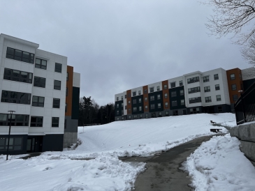 An image of two apartment buildings on a hill during a snowy day. 