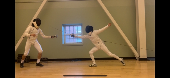 Two people in full white fencing uniforms fight with swords.