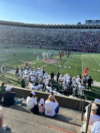 A photo of the Dartmouth football players standing on the sideline of the Dartmouth vs Harvard football game