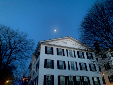 Picture shows white Dartmouth building next to Dartmouth Hall, taken in the early evening in spring