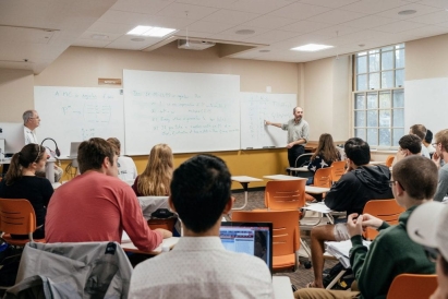 a Dartmouth professor in front of a whiteboard teaching Dartmouth students in a classroom.