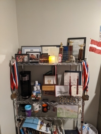 My shelf showcasing my academic awards, family pictures, and coffee machine