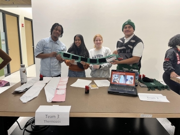 An image of four students holding up a green thermal wrap in a presentation