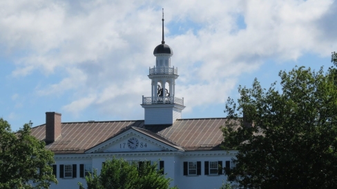  The white, round, cupola on top of Dartmouth Hall, a timber and brick building in the colonial style painted white with black window shutters. 