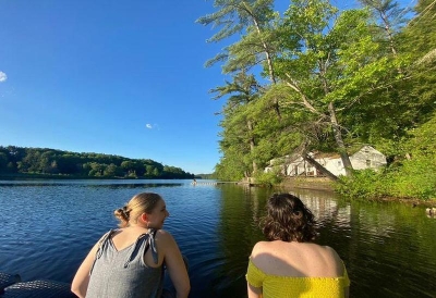 Two women sitting by the Connecticut River on the docks. 