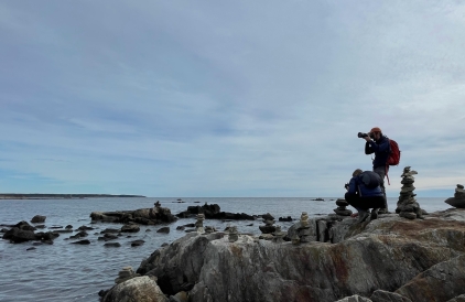 Wyatt with his camera on a bunch of rocks in the sea