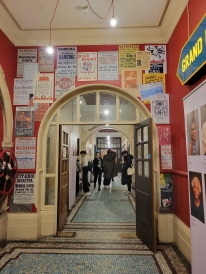A high opening in the shape of a door surrounded by red walls with posters.