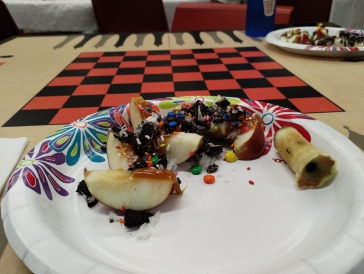 sliced apples with m&m's, caramel, crushed oreos, coconut flakes, and sprinkles