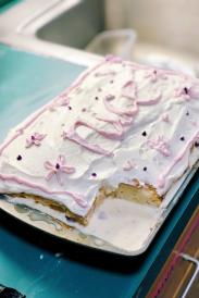 Tres leches cake with pink and white frosting that says "nice" in cursive. 