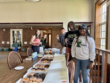 Three UGAs and two Russell Sage residents pose in the Hyphen for a photo with donuts and wellness making kits!