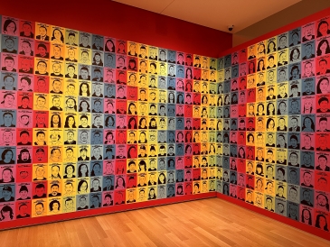 An image of the colorful red, purple, orange, yellow, green, and blue faces in a Hood Museum exhibit.