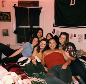 Water polo social! Abbi and her water polo team mates sitting on a dorm room bed and smiling during a team social