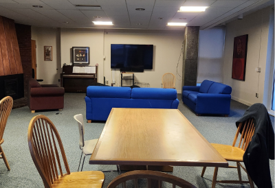Common room of Brown and Little with couches, chairs, tables, and a TV. 