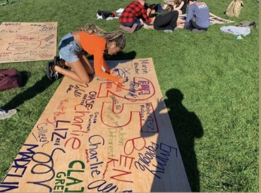 someone signing a wooden board