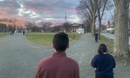 Image of a pink and purple sky behind Baker Library from the Dartmouth Green.