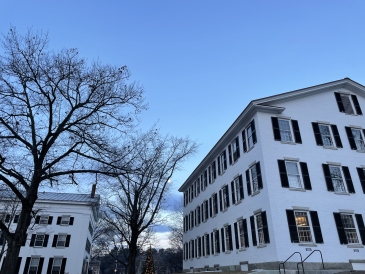 Dartmouth Hall in the early morning with a full moon and a lighted Christmas tree in the background