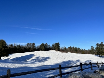 A picture of a vast snow covered landscape beyond a wooden fence.