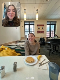 A BeReal. The big photo is me wearing a tan patterned sweater while smiling with some pancakes and a banana. The small photo is a selfie of Jordan smiling.