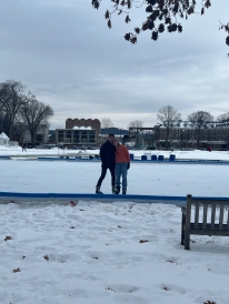 A photo taken across the street from the ice skating rink on the Green. On the rink, Luca and I pose for a photo in our skates.