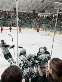 A photo of Dartmouth hockey players celebrating with an on-ice hug after a goal
