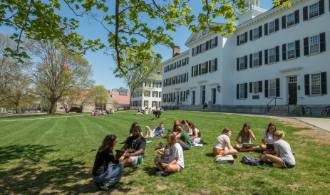 A photo of students sitting on the lawn outside of Dartmouth Hall, having class