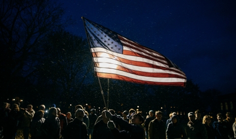 A photo of a person holding an American flag during a Veteran's Day ceremony