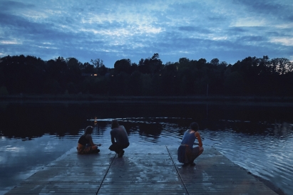 Three people by a river on a dock