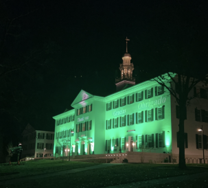 Picture of Dartmouth Hall at night with green lighting and the phrase "thank you" projected onto the building in multiple languages