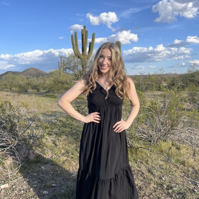 A girl in a black dress with a desert landscape background