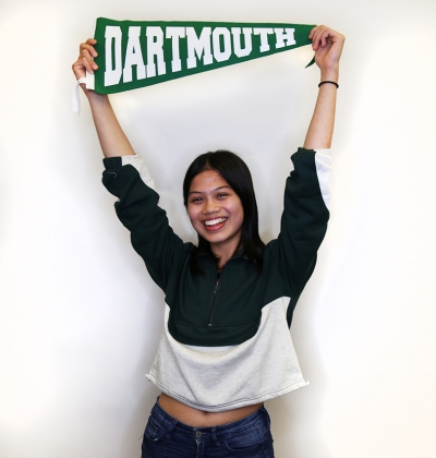 Student smiling for photo holding Dartmouth pennant over head