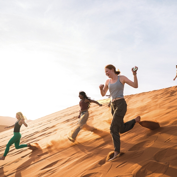 A photo of students racing down the sand dunes of the Namib