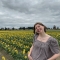 Julia standing in a field of daffodils in a pair of jeans and a striped red top.