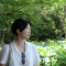 Youmi looking to the side in front of greenery