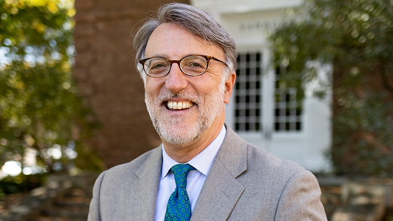 A photo of Lee Coffin, Vice Provost for Enrollment and Dean of Admissions and Financial Aid, standing in front of Sanborn Library on Dartmouth's campus