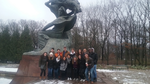 a group of students standing under the Frederic Chopin monument in Poland
