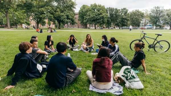 A photo of students sitting in a circle on the Dartmouth Green having a conversation