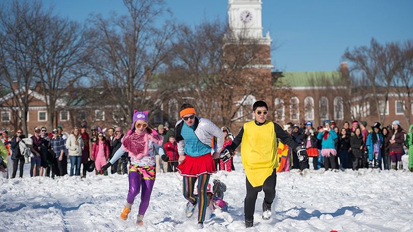 students dressed in colorful costumes pulling sleds in a human dogsled race