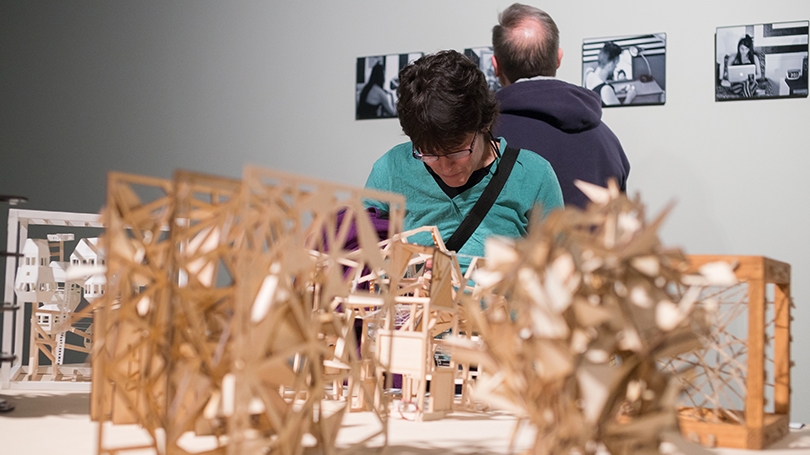 a person looking at 3 dimensional works of art cut from wood