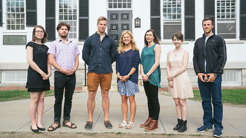 a group of students standing together outside of a white building