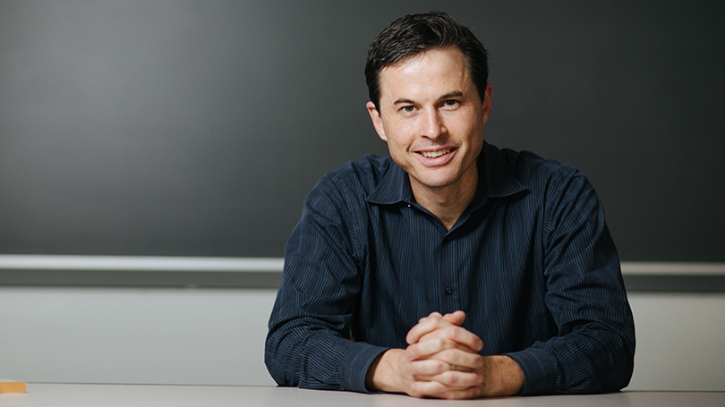 Brendan Nyhan sitting in front of a blank blackboard