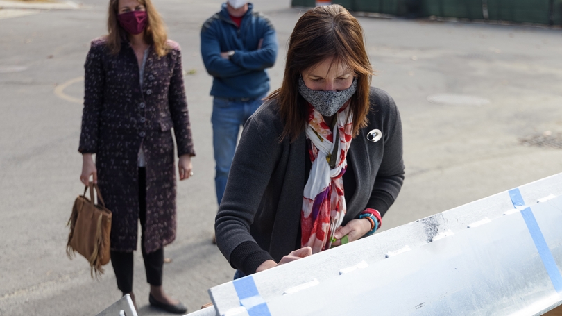 Professor of Environmental Sciences Elizabeth Wilson, the institute's founding director, signs the final beam.