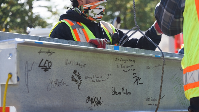 Construction workers, administrators, and faculty put their signatures on the building's final beam, a topping-off tradition.