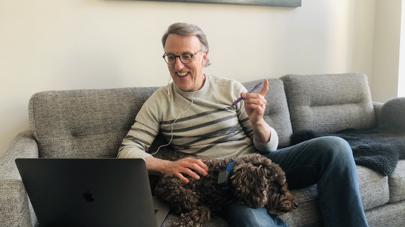 Lee Coffin, and his dog, sit on his couch. 