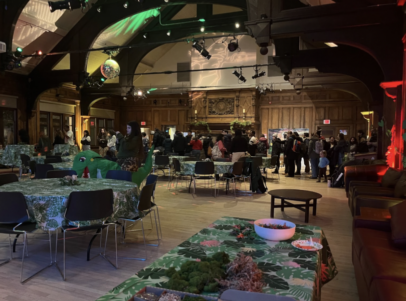 A long line of people in a dark wood paneled room filled with many tables with green table cloths on them
