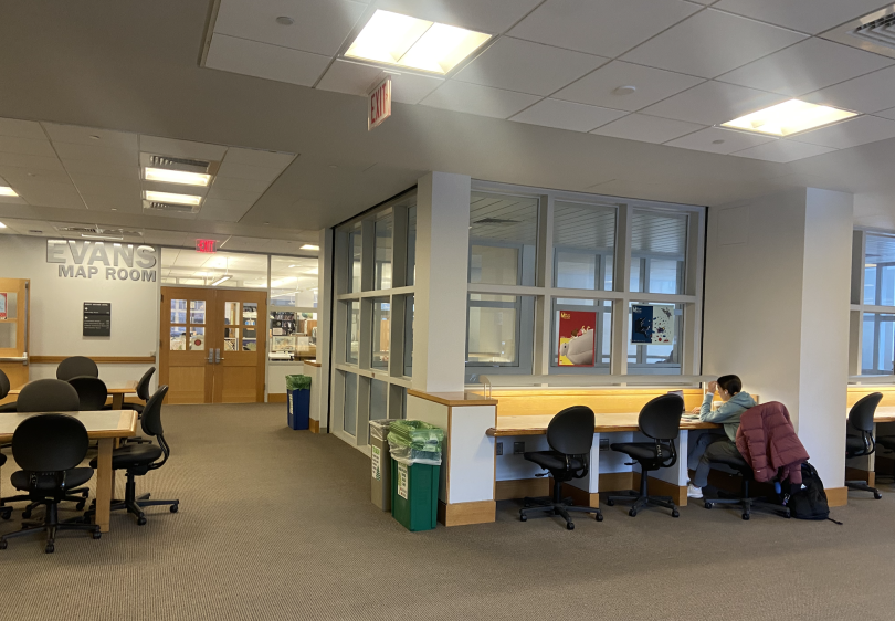 An L-shaped room with a window around the right perimeter. Desks line the right wall, and a table is on the right. The back wall has a door that leads to the Evans Map Room.