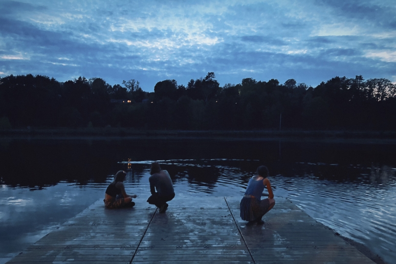Three people at the river docks during twilight